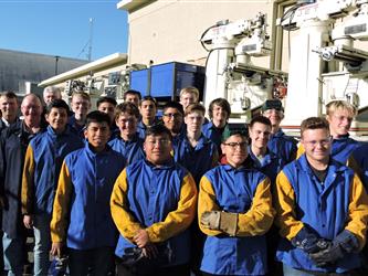 High school students in welding gear standing outside with woodworking equipment on a delivery truck