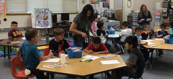 children working at desks while staff help