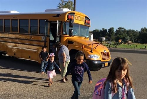 Elementary students unloading from a school bus
